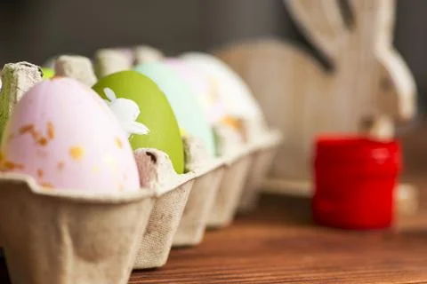 Colorful easter eggs, multi-colored paints and brushes on wooden table. Prepa Stock Photos