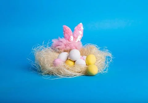 Colorful easter eggs in nest on blue background. Stock Photos