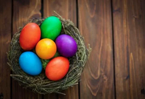 Colorful Easter eggs in the nest on the old wooden background  Stock Photos