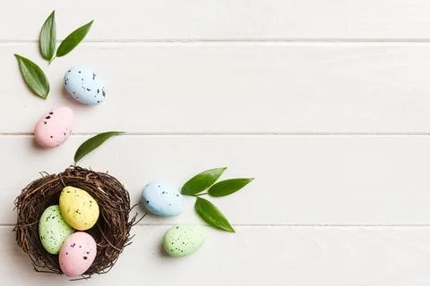 Colorful easter eggs in nest on table background with copy space top view 库存照片