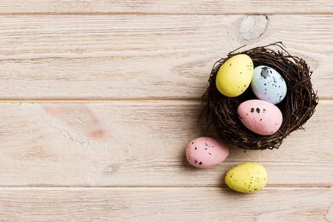 Colorful easter eggs in nest on table background with copy space top view 库存照片