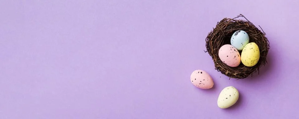 Colorful easter eggs in nest on table background with copy space top view Stock Photos