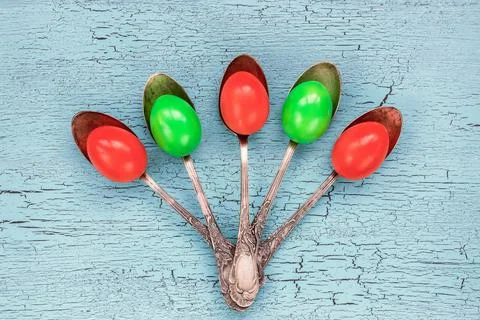 Colorful Easter eggs in old silver spoon on bright background. Top view Stock Photos