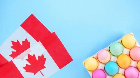 Colorful Easter eggs pack and two canadian flags on blue background with s... Stock Photos