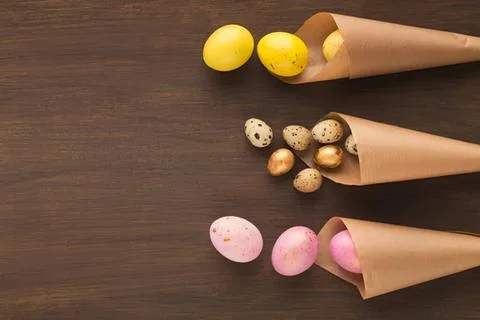 Colorful easter eggs in paper cones on wooden surface Stock Photos