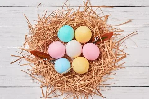 Colorful easter eggs in paper nest on a white background, top view. Easter .. Stock Photos