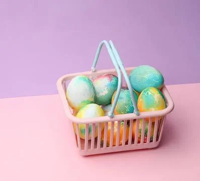 Colorful easter eggs in a pink basket on pastel background Stock Photos