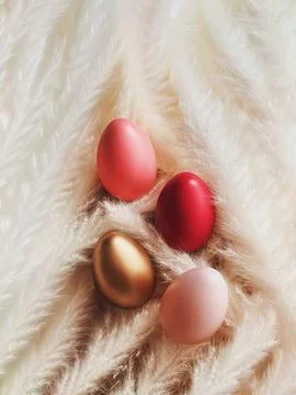 Colorful Easter eggs in pink, red, gold, and light pink blending with fluff.. Stock Photos