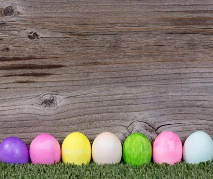 Colorful Easter eggs resting on grass with rustic wooden background Stock-Fotos