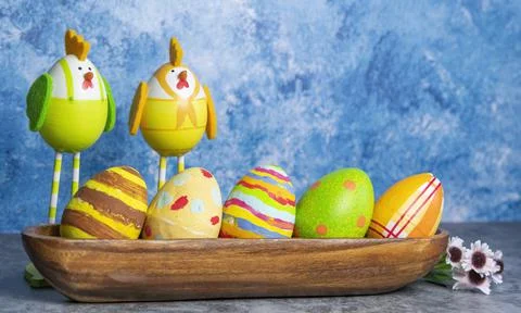 Colorful Easter eggs in a row and eggs in form of chicks with long legs on a  Stock Photos