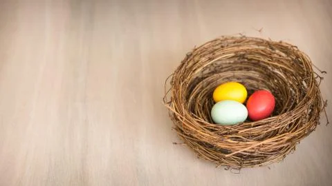 Colorful Easter eggs in a rustic nest or basket on wooden background. Foto stock