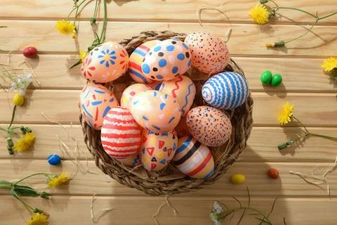 Colorful Easter Eggs in Rustic Wicker Basket Stock Photos
