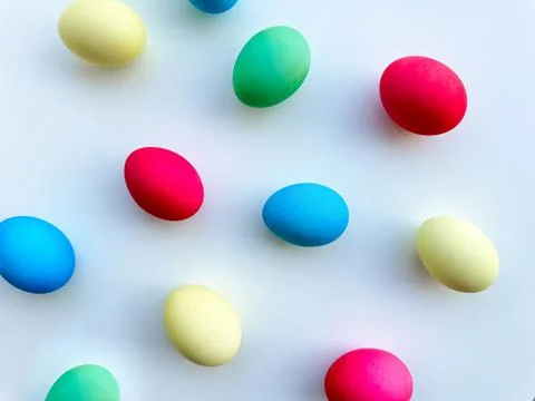 Colorful Easter eggs scattered on white background, flat lay composition for Stock Photos