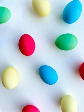 Colorful Easter eggs scattered on white background, flat lay composition for Stock Photos