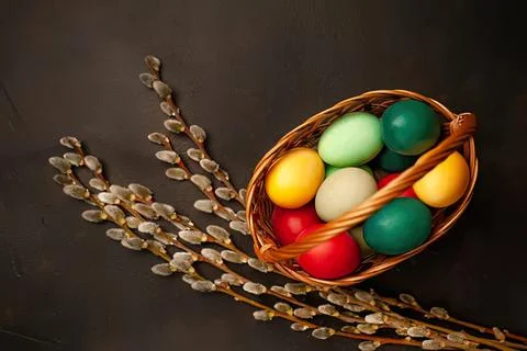 Colorful easter eggs in a small basket with pussy willow branches Stock Photos