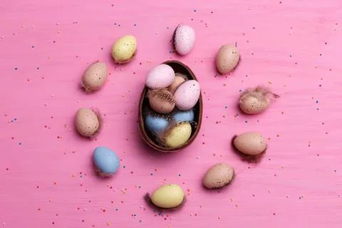 Colorful easter eggs in a small brown basket on pink background Stock Photos
