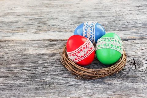 Colorful Easter eggs in small nest on wooden background Stock Photos