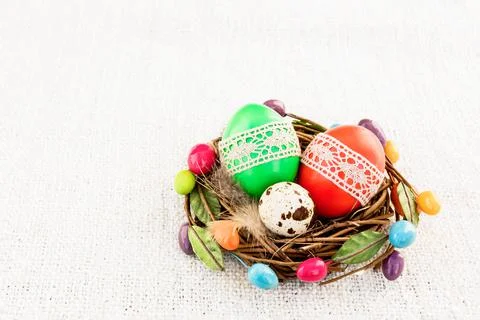 Colorful Easter eggs in small nest on light background Stock Photos