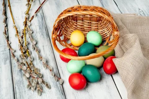 Colorful easter eggs in a small wicker basket on wooden table Stock Photos