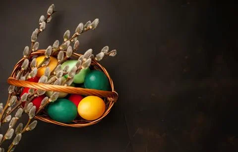 Colorful easter eggs in a small wicker basket with pussy willow Stock Photos