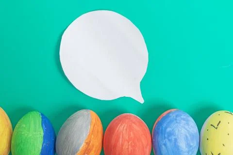 Colorful Easter eggs with speech bubble on bright green background, Top view Stock Photos