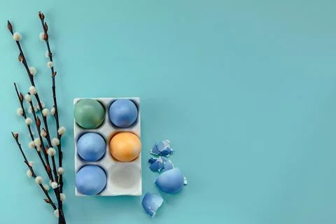 Colorful Easter eggs in a stand on a blue background next to willow branches Stock Photos