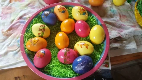 Colorful easter eggs with stickers, decorated bowl, hand puts egg on table Stockbeeldmateriaal 76281899
