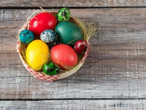 Colorful easter eggs in straw nest on a wooden table Stock Photos
