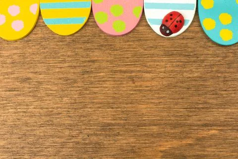 Colorful Easter eggs upper border, old rustic wood background, flat lay desig Stock Photos