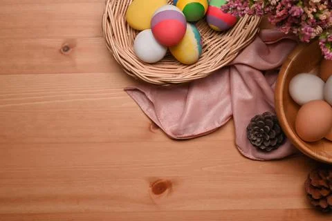 Colorful Easter eggs in wicker basket on wooden background with copy space. Stock Photos