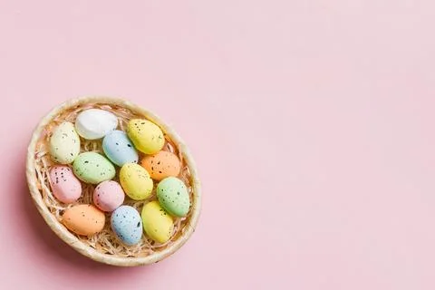 Colorful Easter eggs in wicker basket against colored background, closeup. .. Stock Photos