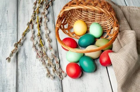 Colorful easter eggs in a wicker basket on wooden table Stock Photos