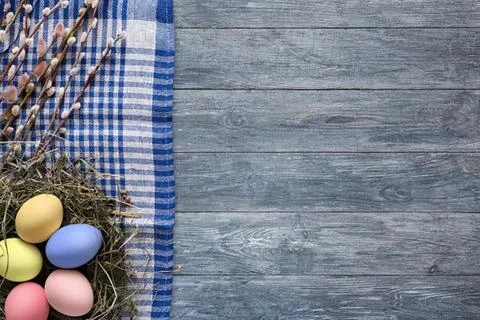 Colorful easter eggs in a wire basket on wooden surface Stock Photos