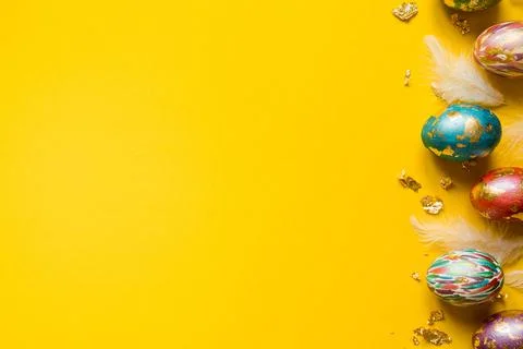 Colorful Easter eggs on yellow background, copy space. Greeting card or banner Stock Photos