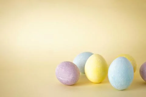 Colorful easter eggs on yellow background, space for text. Stock Photos