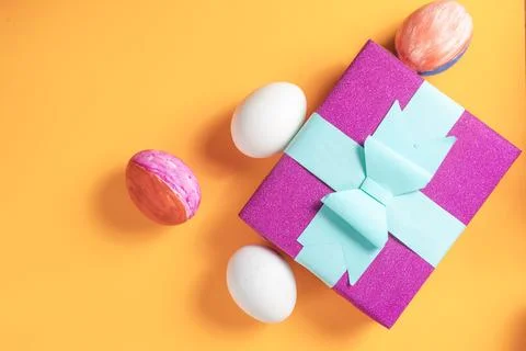Colorful Easter gift with painted eggs on an orange background Stock Photos