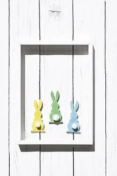 Colorful easter rabbits in white frame on white wooden background. Happy Ea.. Stock Photos