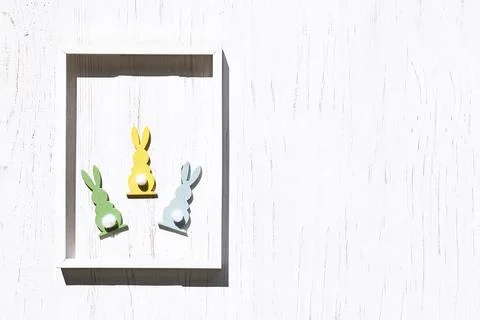 Colorful easter rabbits in white frame on white wooden background. Happy Ea.. Stock Photos