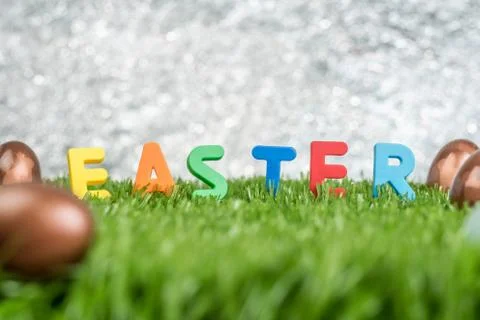 Colorful easter word and rabbit stamp on eggs on green grass field at outdoor Stock Photos