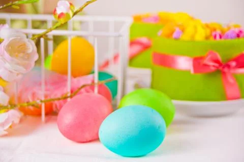 Colorful eggs for Easter day and small cakes on the background. 库存照片