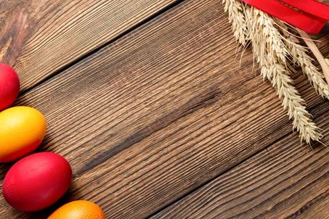 Colorful eggs for Easter with ears of grain on brown wooden background Stock Photos