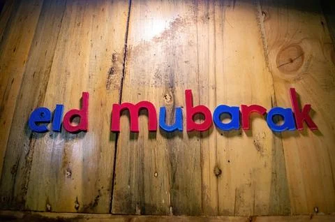 Colorful "Eid Mubarak" letters on a rustic wooden background, celebrating t.. Stock Photos