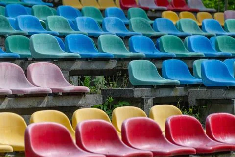 Colorful empty stadium seats in rows of red, yellow, green, and blue Фото
