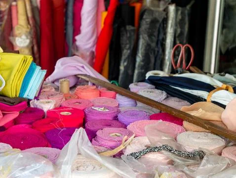 Colorful fabric rolls and textile swatches displayed at Bangkok market stal.. 스톡 사진