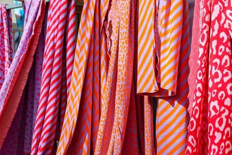 Colorful fabrics with various patterns hanging at market stall Stock Photos