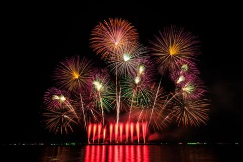 Colorful Festive Fireworks Exploding Above Dark Water During A Night Celebr.. Foto stock