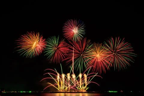 Colorful Festive Fireworks Exploding In The Night Sky Over A Waterfront Sti.. Stock Photos