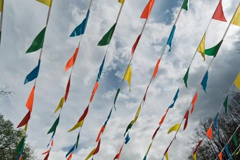 Colorful festive flags flutter in the wind against a dramatic cloudy sky, Foto stock