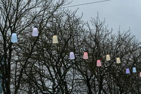 Colorful festive string lights line hanging over city street on winter day,.. Stock Photos