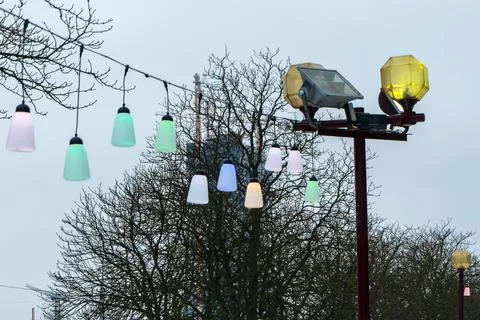 Colorful festive string lights line hanging over city street on winter day,.. Foto stock